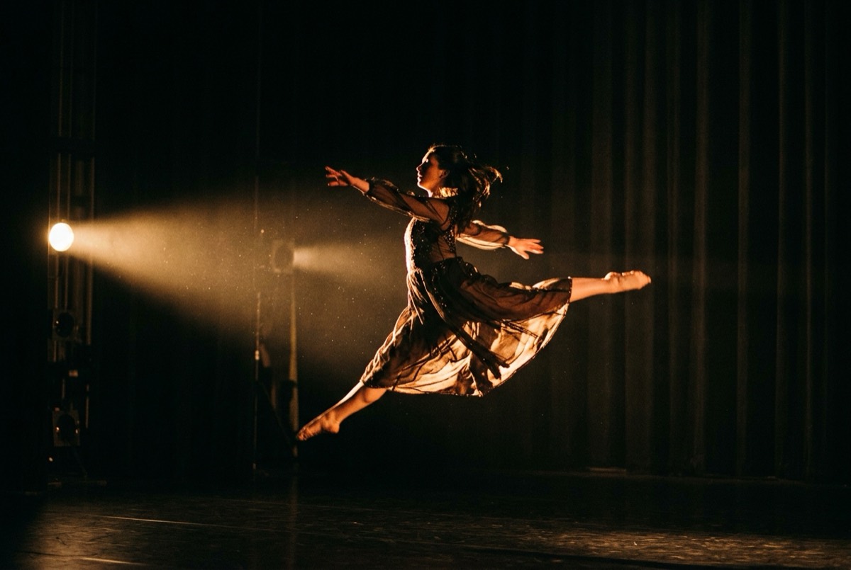 A dancer mid-leap under a stage light